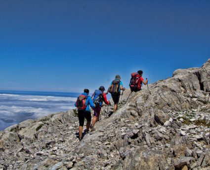 Grupo en la circular al Urriellu caminando sobre el mar de nubes en Picos de Europa